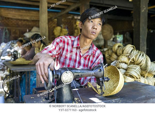 Myanmar (ex Birmanie). Sagaing, region of Mandalay. Rural village. Young man working at Manufacture of straw hats