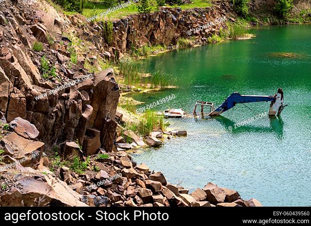 Drowned in flooded basalt quarry excavator. Summer Basalt Pillars Geological Reserve and Basaltove lake, Rivne region, Ukraine
