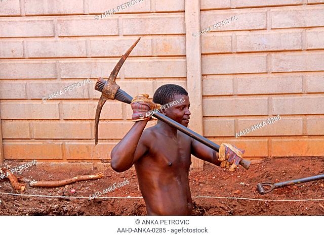 Construction worker with pick-axe digging a hole for a small swimming pool, Moreleta Park, Pretoria, Gauteng, South Africa