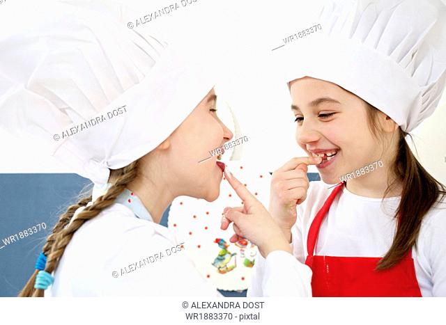 Two little girls with chef's hat kidding around, Munich, Bavaria, Germany