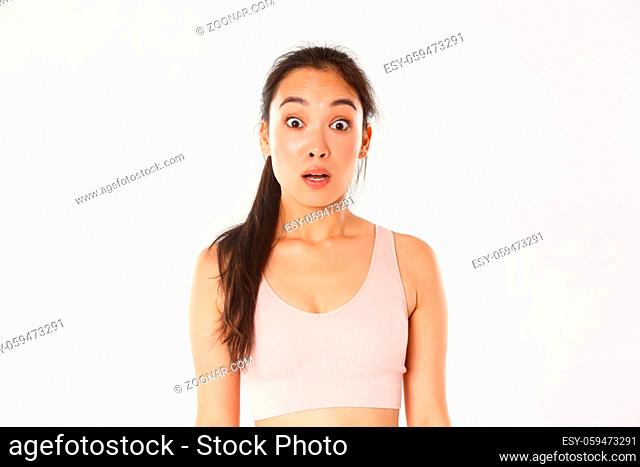 Sport, wellbeing and active lifestyle concept. Close-up of surprised and startled asian fitness girl, sportswoman in sportsbra looking confused with dropped jaw