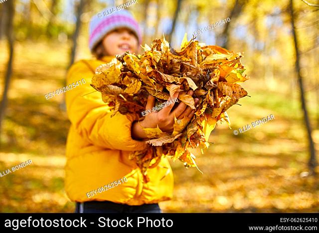 Happy adorable child girl laughing and playing yellow fallen leaves in autumn outdoors, Happy moment