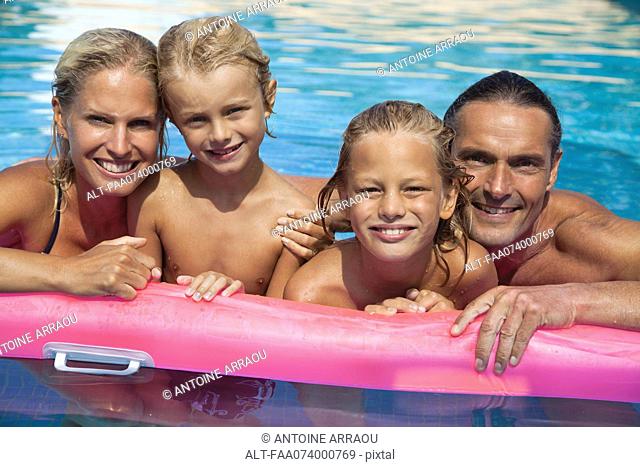 Family relaxing together in pool, portrait
