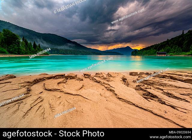 Storm during sunset with sand structures on the shore of the lake Walchensee in the Bavarian Prealps