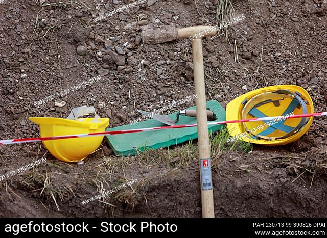13 July 2023, Saxony-Anhalt, Wernigerode: Helmets and spades lie at the site of archaeological investigations at the former Himmenpforte monastery in...