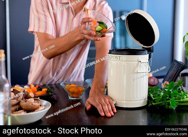 Midsection of biracial man cleaning waste in kitchen
