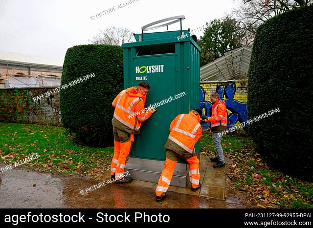 27 November 2023, North Rhine-Westphalia, Cologne: The ""Holy Shit"" dry toilet is moved to its place in the Volksgarten by employees of the City of Cologne