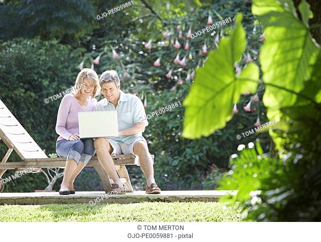 Couple outdoors in yard with laptop