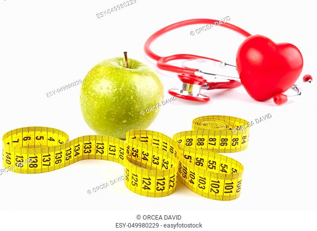 wet apple close-up with drops and yellow measure tape and red stethoscope and heart isolated on white