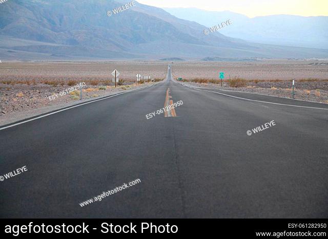 The never ending road during the dusk of a sunset in the Death Valley desert in California