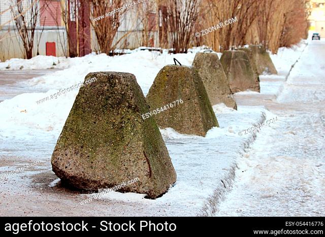 antiterrorist pyramidal concrete pedestals near the house beside the road against the entry of vehicles. Relevant when the danger of terrorist attacks