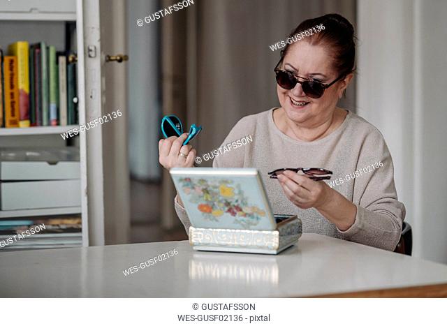 Senior woman taking sunglasses out of jewelry box at home