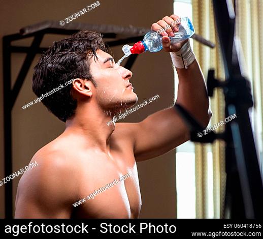 The thirsty man drinking water in sports gym