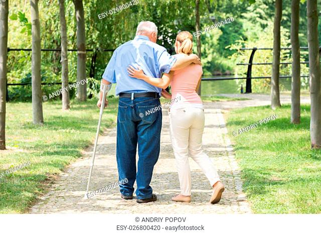 Photo Of A Young Woman With Her Disabled Father Standing In Park