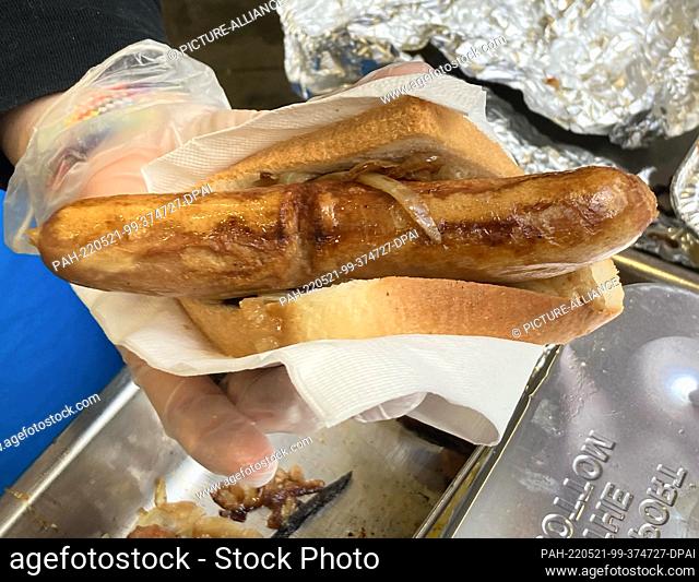 21 May 2022, Australia, Sydney: An election worker offers a fried sausage in toast outside a polling station at Fort Street Public School in Sydney, Australia