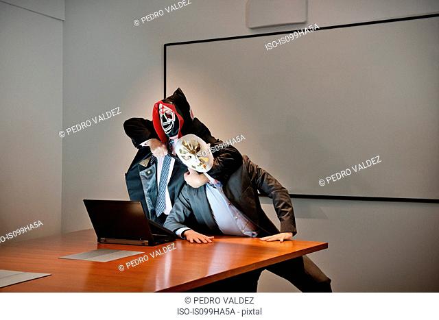 Businessmen in masks fighting over laptop