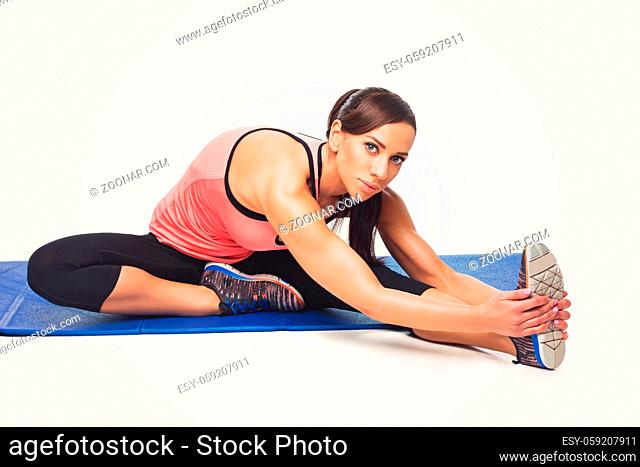 Beautiful young fit sporty woman making sport exercise on blue mat. Isolated over white background. Copy space