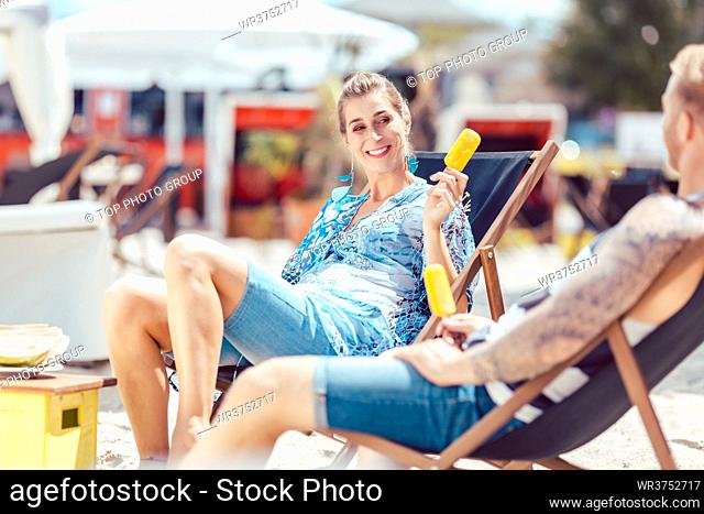 Happy young couple enjoying at beach with popsicles
