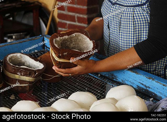 MEXICO CITY, MEXICO - OCTOBER 23: A person pours a mixture of sugar with water into a clay mold in the shape of a skull during the making of the traditional...