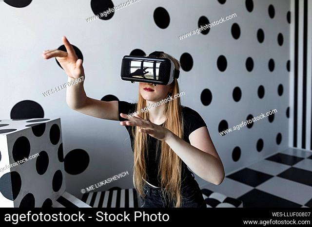 Girl with long hair wearing virtual reality headset by dotted wall