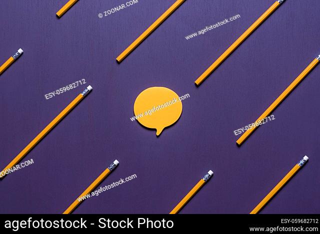 Communication concept with a post-it note, in shape of a speech bubble, surrounded by aligned orange pencils with erasers, on a purple background