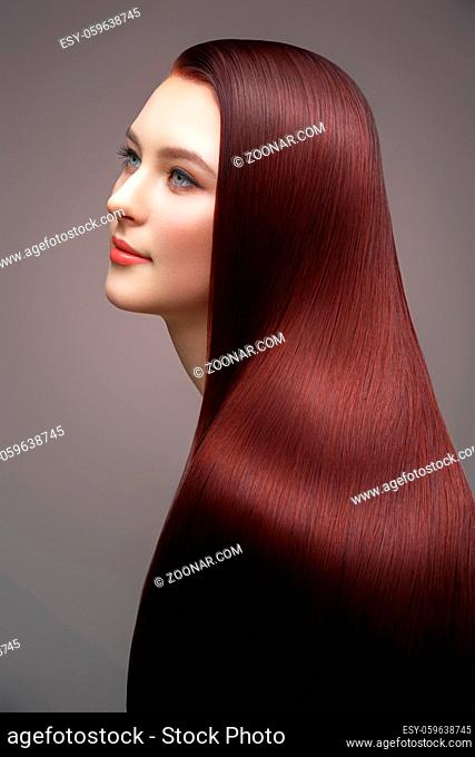 beautiful young woman with long healthy shiny hair. red color. copy space