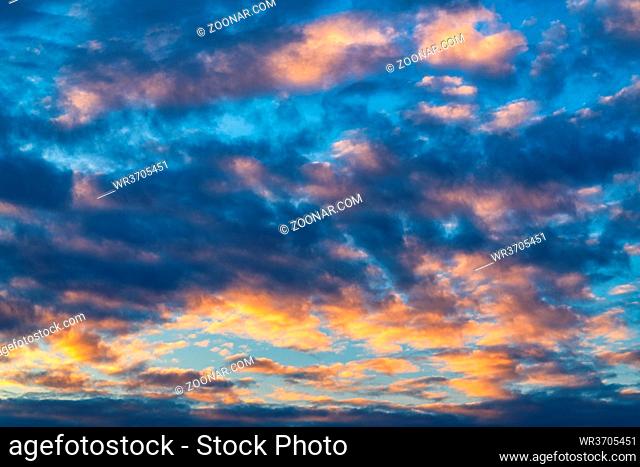 Amazing clouds in blue sky, illuminated by rays of sun at sunset to change weather. Soft focus, motion blur colorful abstract meteorology background