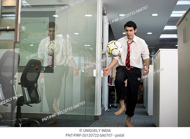 Businessman playing with a soccer ball in office