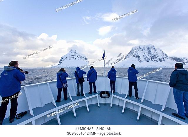 The Lindblad Expedition ship National Geographic Explorer transits Lemaire Channel in late evening light on the west side of the Antarctic peninsula in...