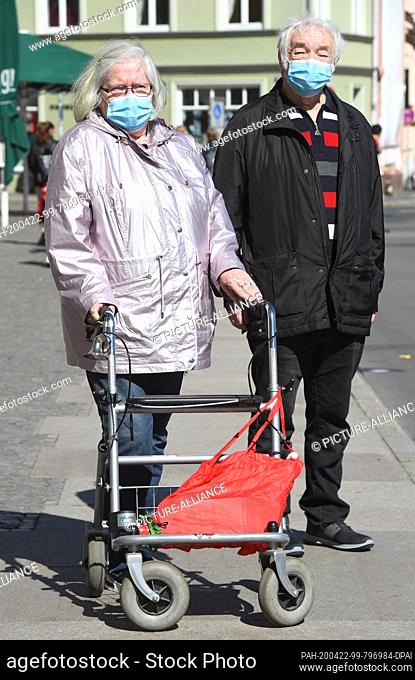 22 April 2020, Mecklenburg-Western Pomerania, Stralsund: Jutta and Harald Schädlich are on the road in the city centre wearing protective masks
