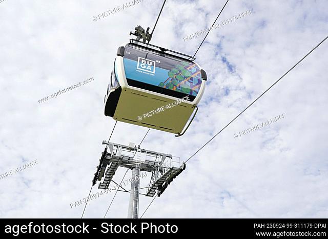 PRODUCTION - 20 September 2023, Baden-Württemberg, Mannheim: A cable car cabin with the inscription ""BUGA"" hovers above the grounds of the Federal...
