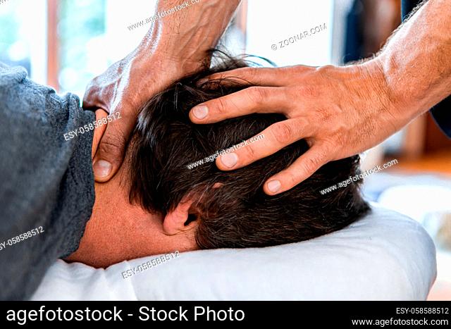 A male sports massage therapist doing head and neck massage. Therapeutic body massage treatment. Osteopathy and sports injury rehabilitation