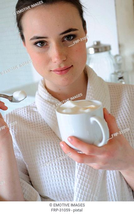Young woman drinking coffee in bathroom