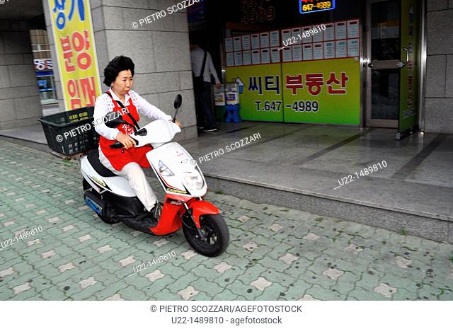 Busan (South Korea): a woman driving a scooter on the sidewalk in Nam-gu neighborhood
