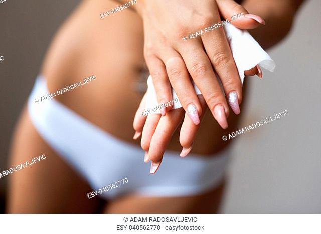 Young woman in panties clean hands with wet wipes, body and panties in background