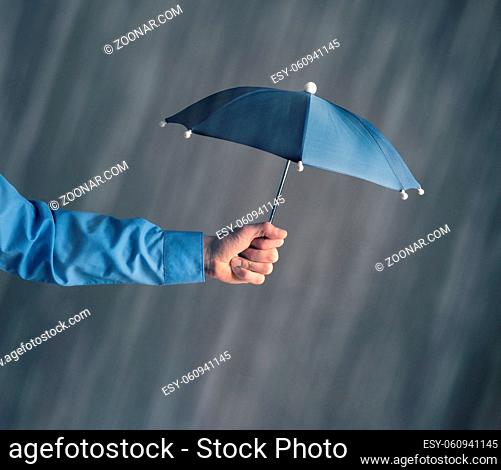 Hand of a businessman with an umbrella in rain, protection or safety concept