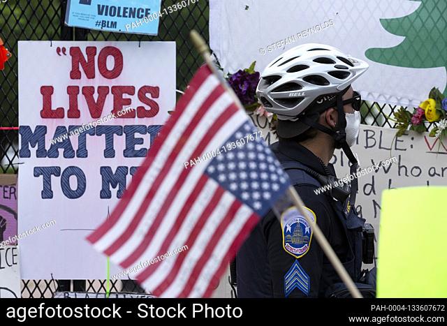A police officer looks at signs on the fence surrounding Lafayette Square near Black Lives Matter Plaza in Washington D.C., U.S