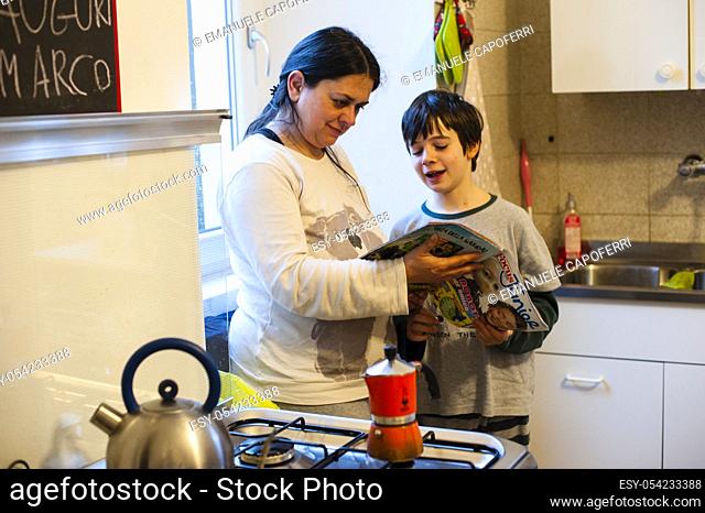 Mother and son reading magazine in the kitchen at home