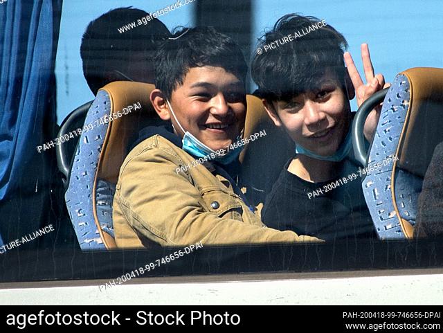 18 April 2020, Lower Saxony, Langenhagen: Two young refugees sit laughing in a bus leaving the tarmac of Hannover airport