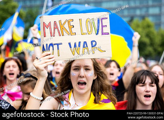 23 July 2022, Berlin: A woman holds a sign reading ""Make love not war"" during Christopher Street Day (CSD). This year's motto for the parade for lesbian, gay