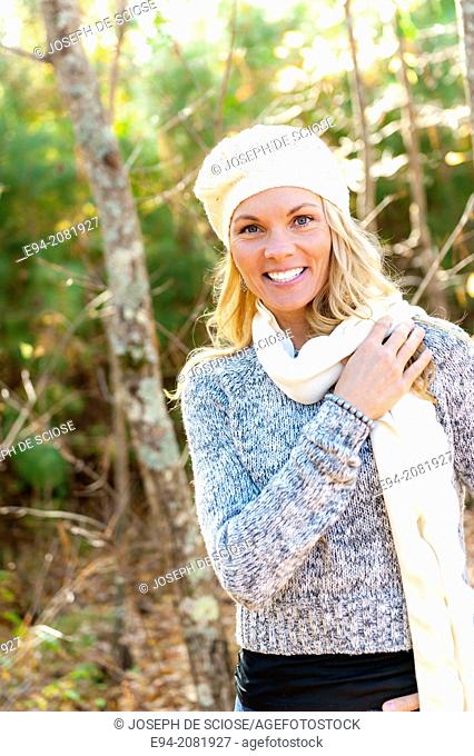 39 year old blond woman wearing a sweater, mini-skirt and boots walking in the forest in the fall