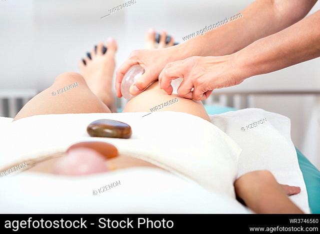 Close-up of a masseuse massaging with stone in spa