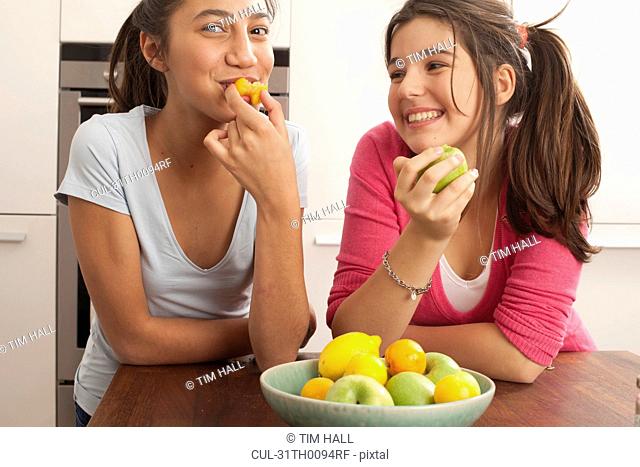 teenage girls smiling , eating fruit