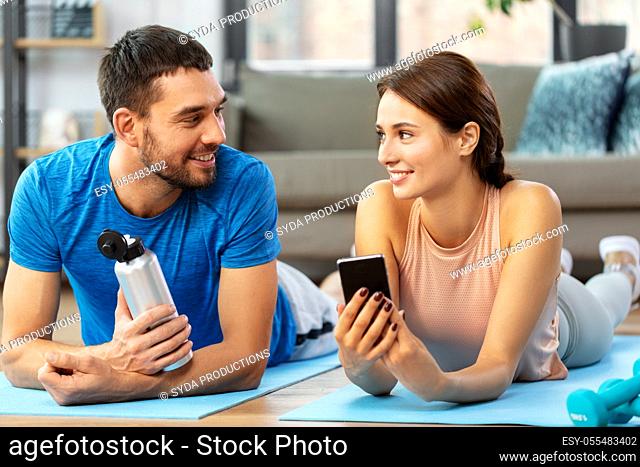 happy couple with smartphone after sports at home