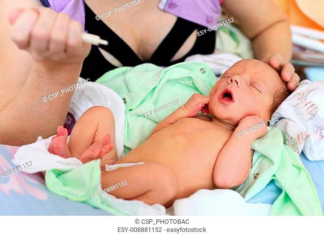 Mother feeding newborn baby milk with syringe