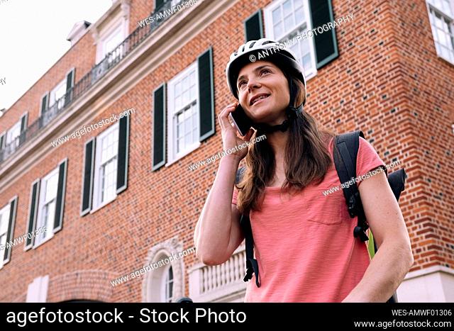 Delivery woman talking on smart phone in front of building
