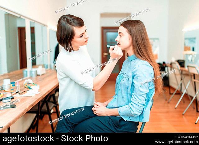Female make up artist work with beautiful woman face, beauty studio on background. Cosmetic salon