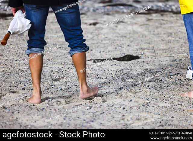 15 October 2023, Rostock-Warnemünde: Two people walking barefoot on the beach in Rostock-Warnemünde. Photo: Frank Molter/dpa