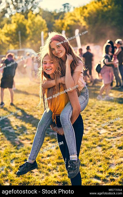 Portrait of happy smiling young girls with colorful paints on faces and clothes. Two friends spending time on holi color festival