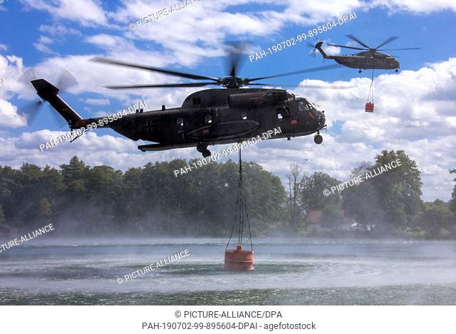 02 July 2019, Mecklenburg-Western Pomerania, Probst Jesar: Two helicopters CH53 of the German Armed Forces each take up 5000 litres of extinguishing water in a...
